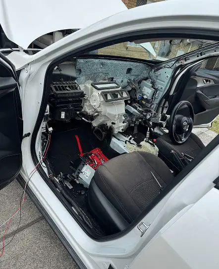 Vehicle interior undergoing dashboard wiring and auto electrical repair work